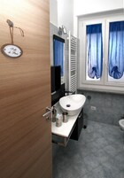 Un baño con puerta de madera, un lavamanos blanco, un espejo y una ventana con cortinas azules.