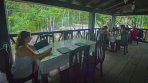 A covered outdoor dining area with tables and chairs, surrounded by lush greenery. - Ecolodge Las Nubes Chiapas (Maravilla Tenejapa)
