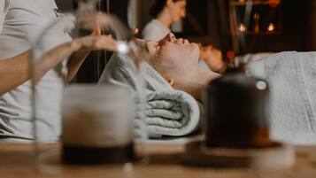 A spa setting with a person receiving a facial treatment, a towel, and a cup on the table.