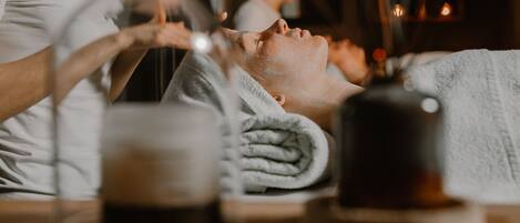 Une scène de spa où une personne reçoit un soin du visage, avec une serviette et une tasse sur la table.