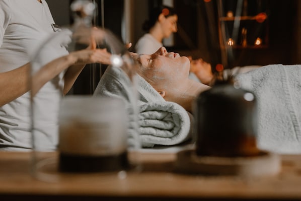 A spa setting with a person receiving a facial treatment, a towel, and a cup on the table. - Marvie Hotel & Health (Split)