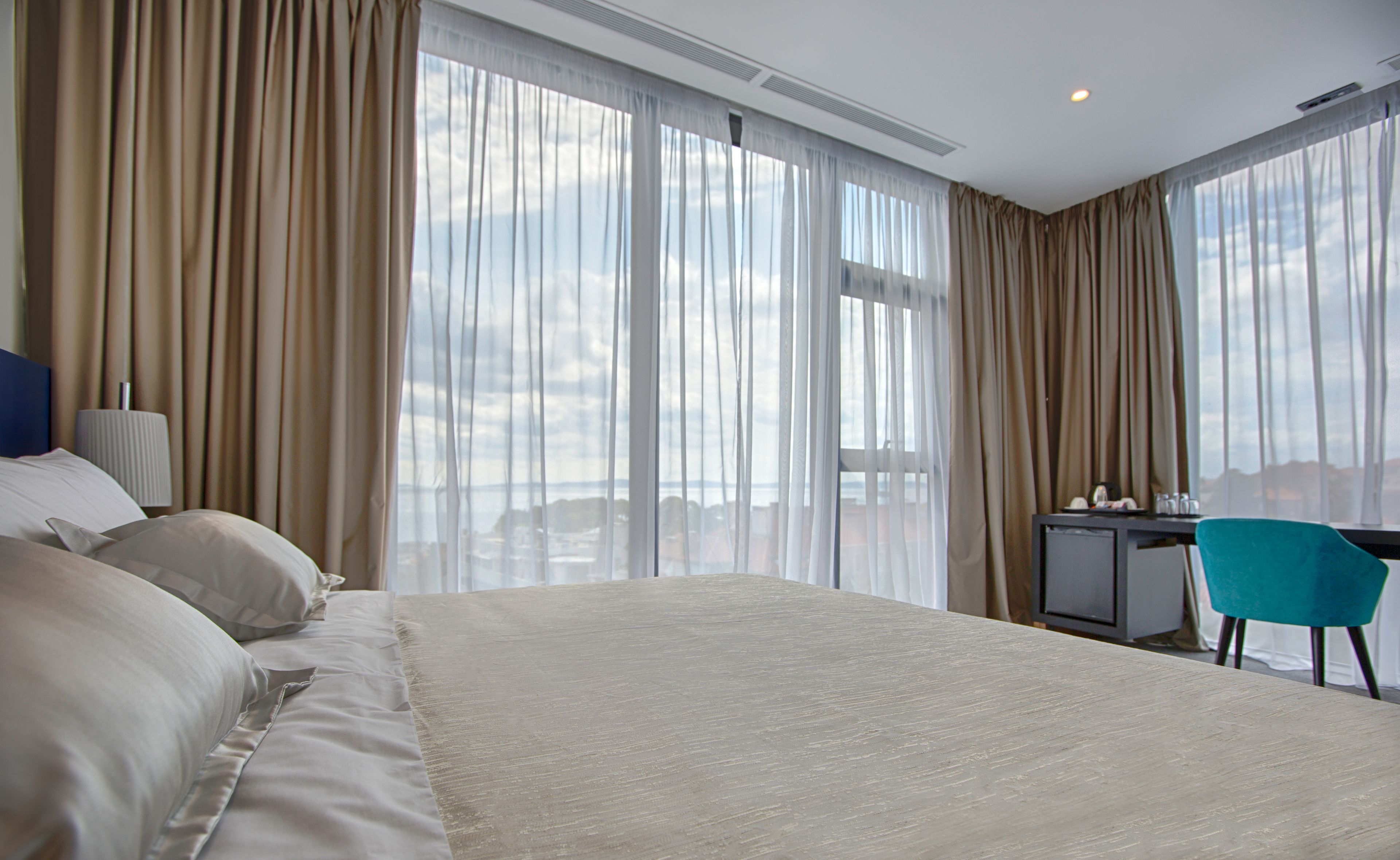A hotel room with a large bed, a desk, and a chair.