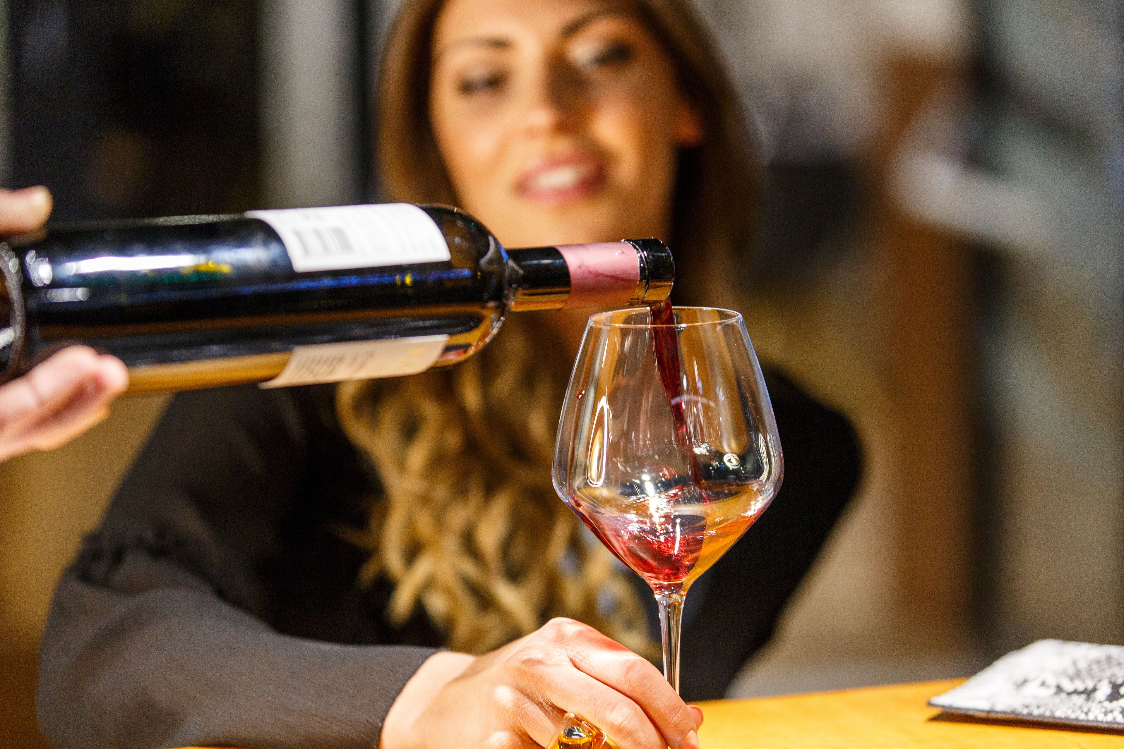 A person pouring wine into a glass.