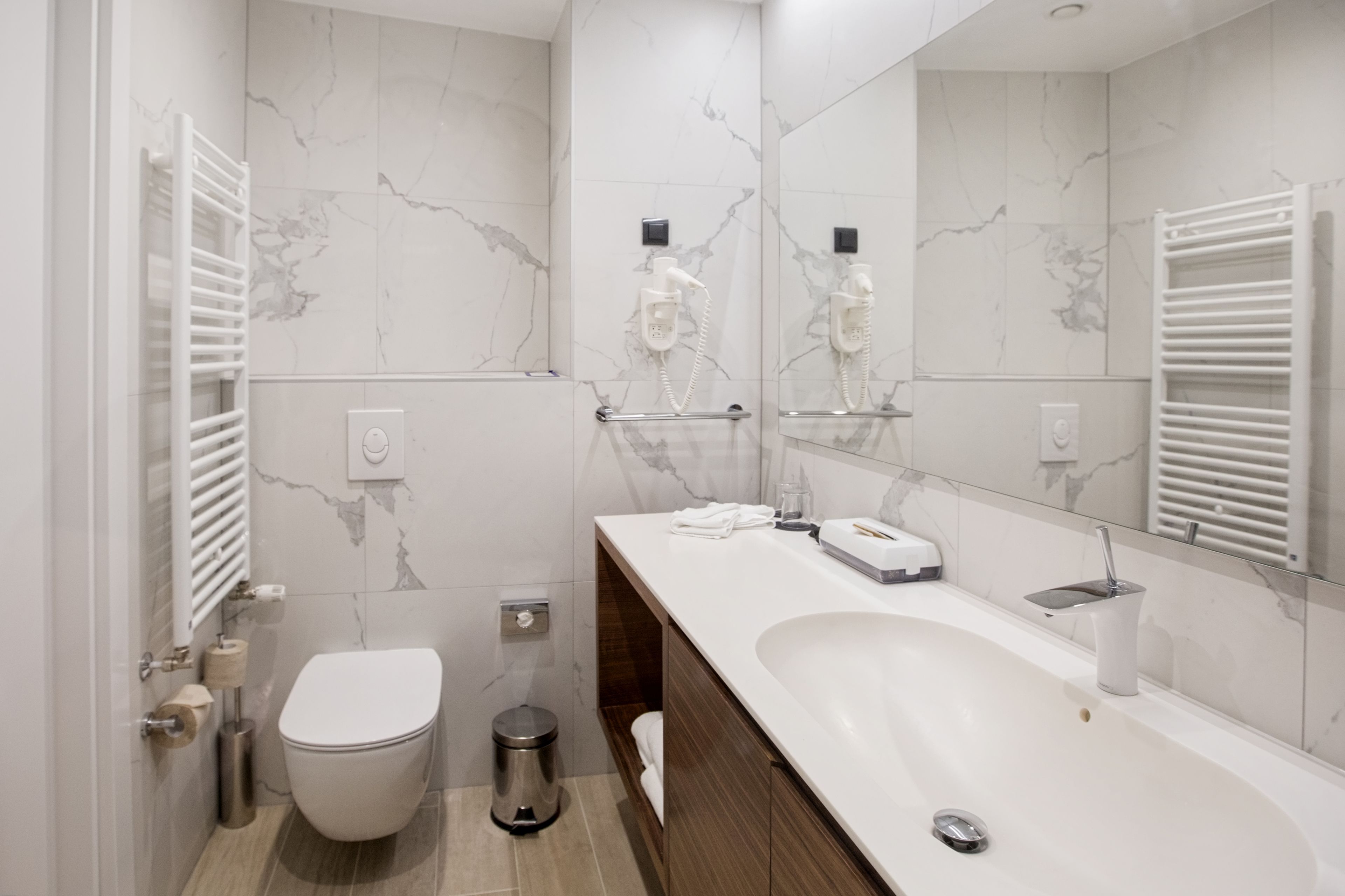 A modern bathroom with a white toilet, a sink with a mirror, and a towel rack.