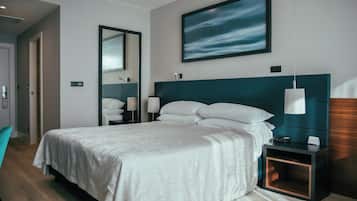 Habitación de hotel moderna con una cama grande, una mesita de noche, un espejo y un cuadro en la pared.