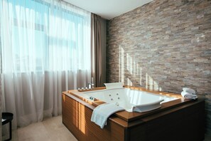 Ein modernes Badezimmer mit einer freistehenden Badewanne, einem Holzkosmetikschrank und einer Wand mit Steinoptik.
