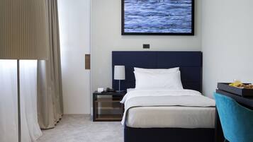 A hotel room with a bed, a nightstand, a TV, a lamp, a chair, and a desk with a tray of food.