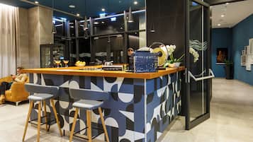 Un espace bar moderne avec un motif géométrique en carreaux, des tabourets de bar et une cloison en verre.