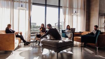 Un espace détente moderne avec des canapés en cuir, une table basse et un ordinateur portable posé sur une petite table.