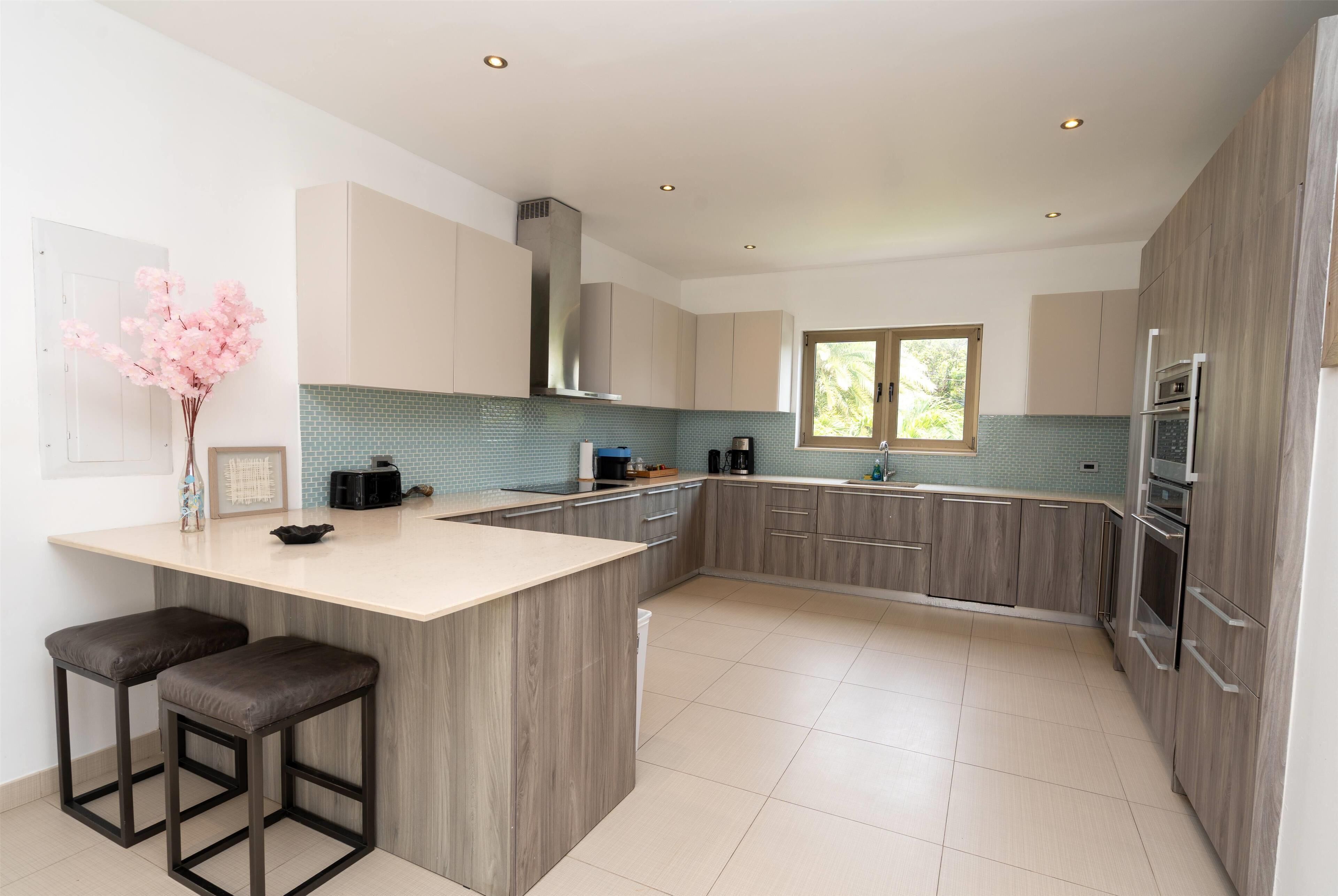 A modern kitchen with a central island, wooden cabinets, and stainless steel appliances.