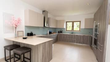 A modern kitchen with a central island, wooden cabinets, and stainless steel appliances.