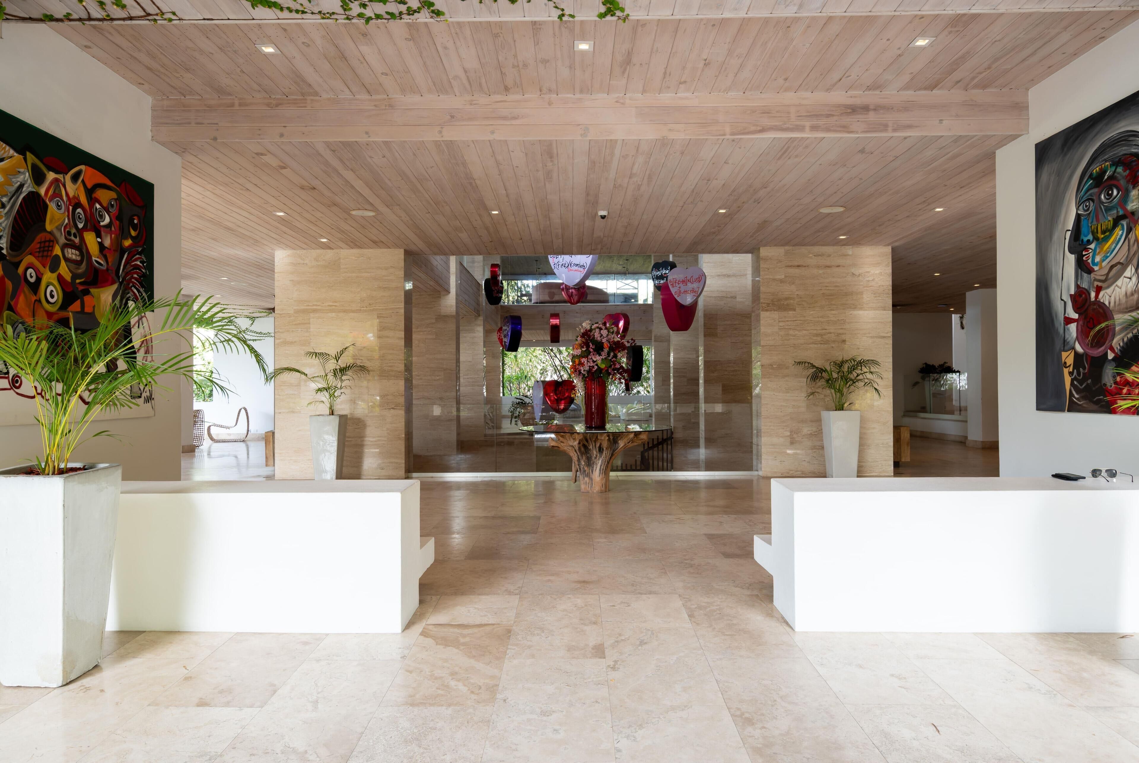 A modern lobby with a wooden ceiling, a reception desk, and potted plants.