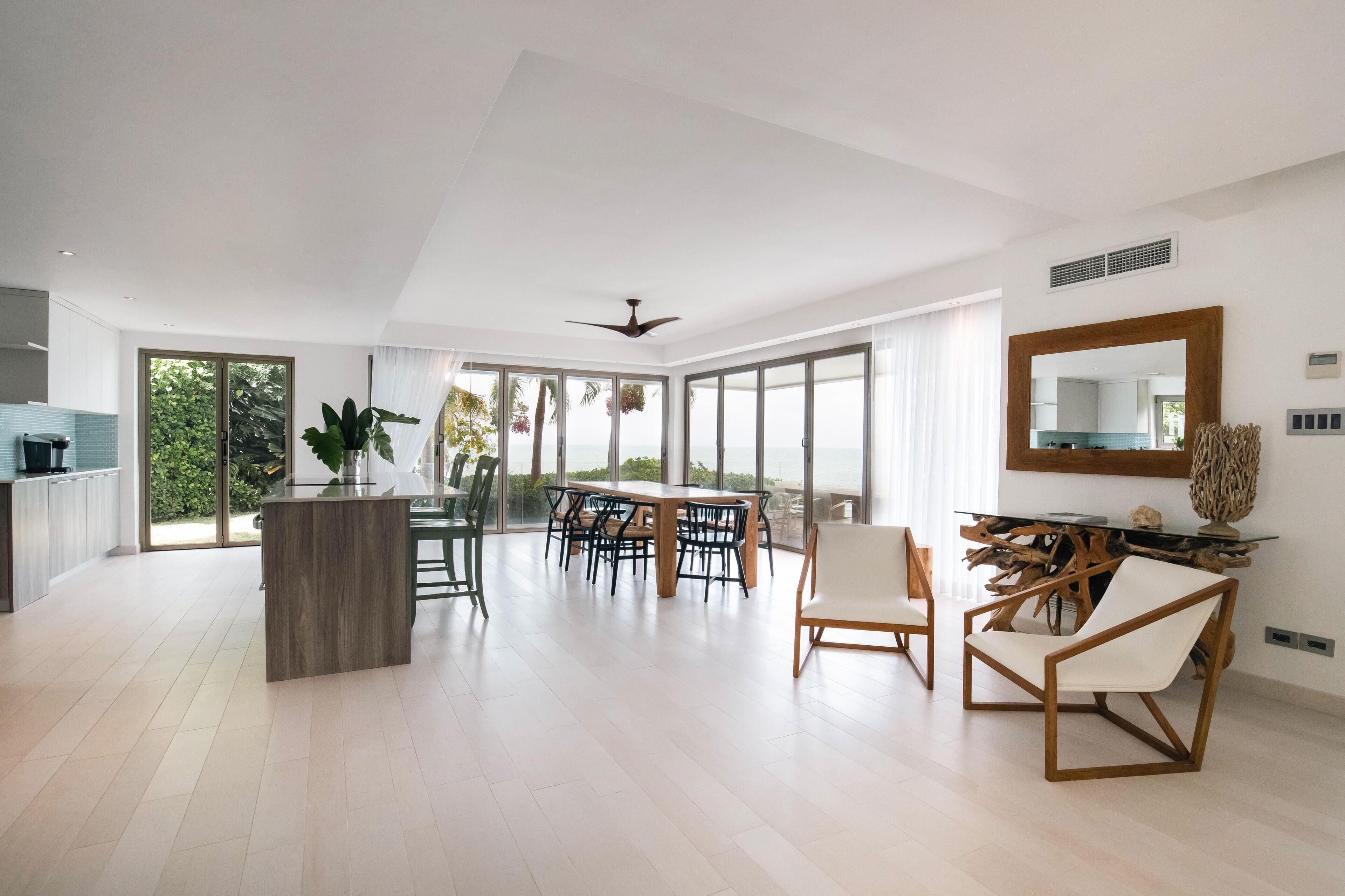 A spacious living area with a dining table, chairs, and a large window offering a view of the outdoors.