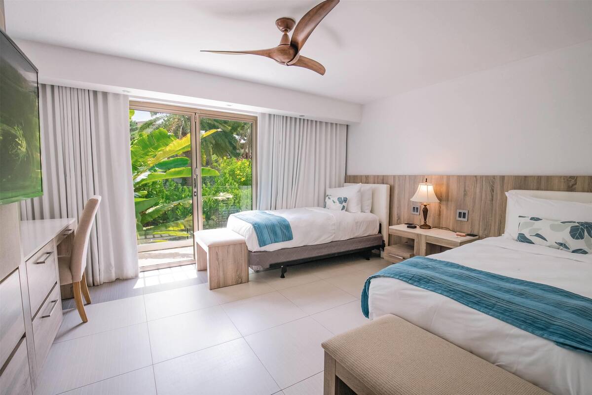 A hotel room with a bed, a desk, a chair, a TV, and a ceiling fan.