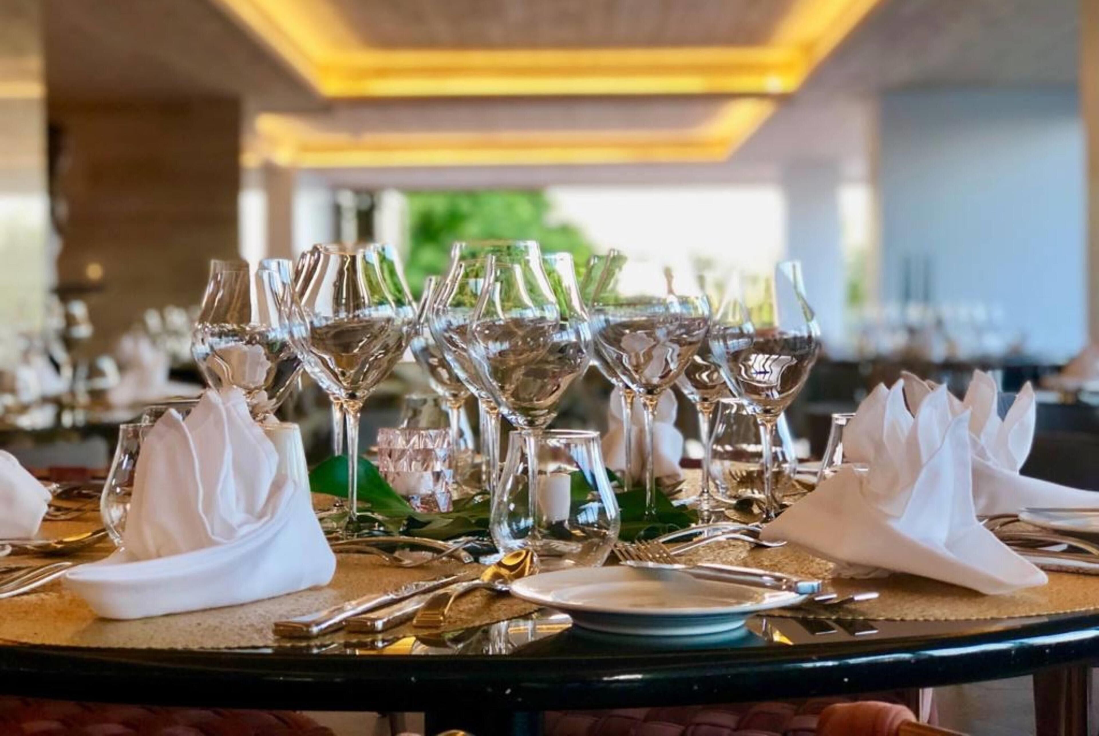 Mesa dispuesta para una cena formal, con varias copas de vino, platos y cubiertos.
