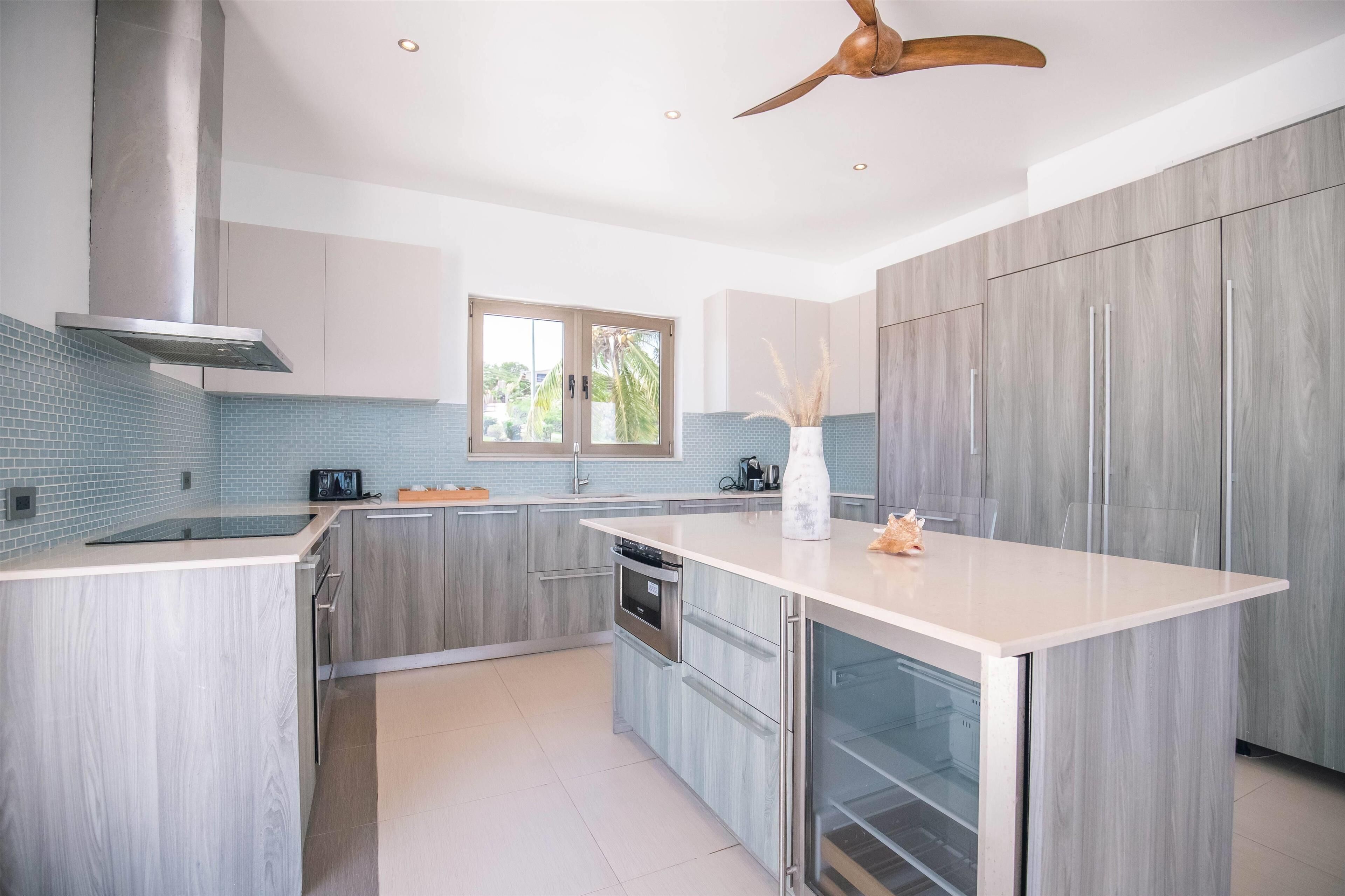 Una cocina moderna con armarios grises, una isla grande y un ventilador de techo.