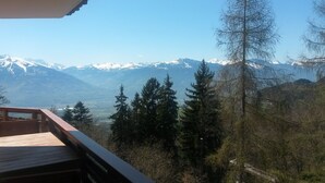 Une vue sur les montagnes depuis un balcon, avec des sommets enneigés en arrière-plan.