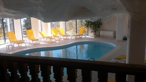 Une piscine avec des chaises longues jaunes et une plante en pot.