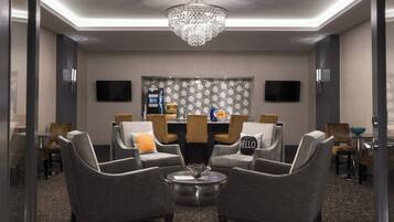 A modern hotel lobby with a chandelier, seating area, and a reception desk.