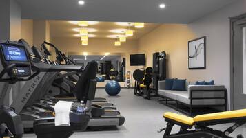 A gym with treadmills, a bench, exercise balls, and a couch.