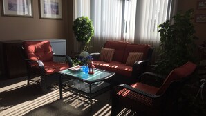A living room with a sofa, chairs, a coffee table, and a potted plant. - Dunlop Motel (Ashfield-Colborne-Wawanosh)