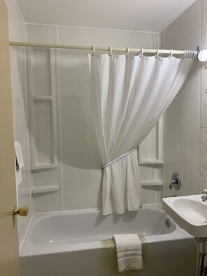 Ein Badezimmer mit einer Badewanne, einer Duschvorhang, einem Waschbecken und einem Handtuchhalter.