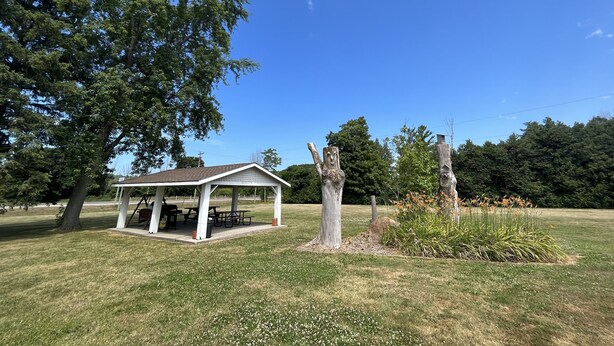 A gazebo with picnic tables in a grassy field, surrounded by trees and a clear sky. - Dunlop Motel (Ashfield-Colborne-Wawanosh)