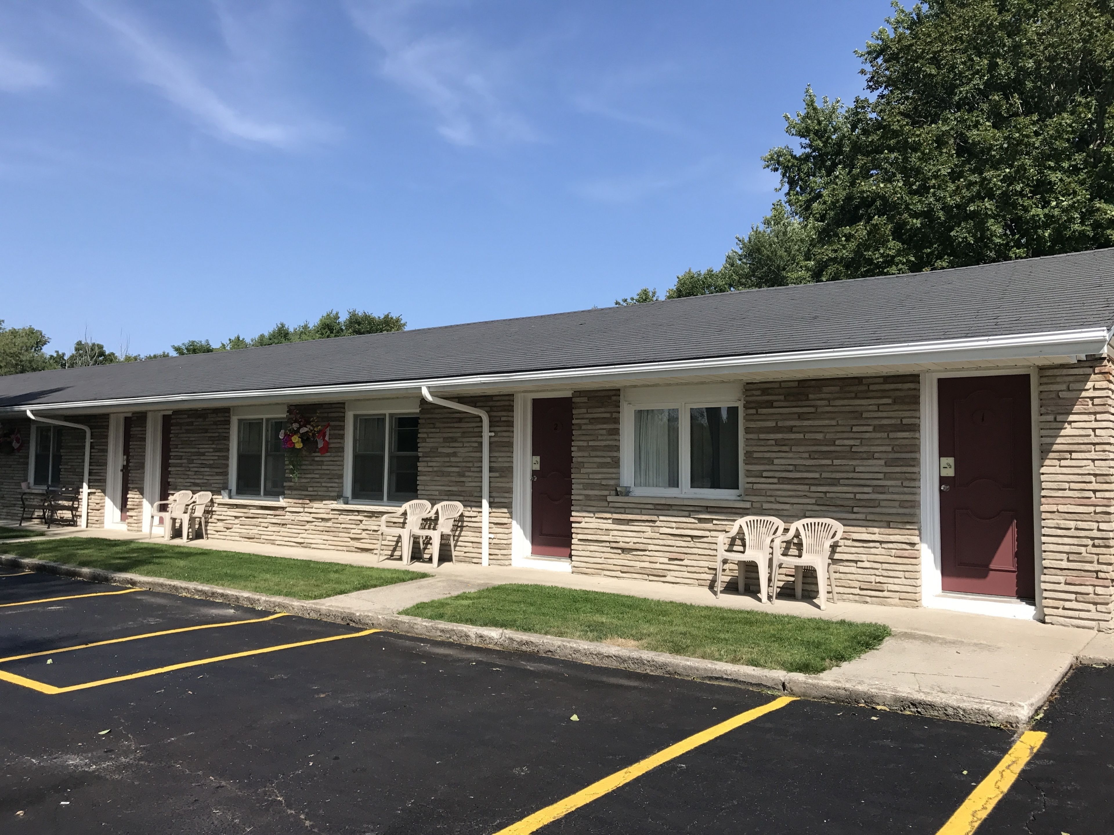 Un motel con fachada de piedra, varias habitaciones y un estacionamiento.