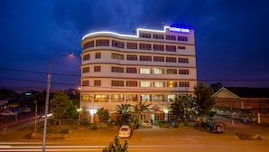 A multi-story hotel with a curved facade, illuminated signage, and a well-lit entrance. - Chester Hotel (Nakuru)