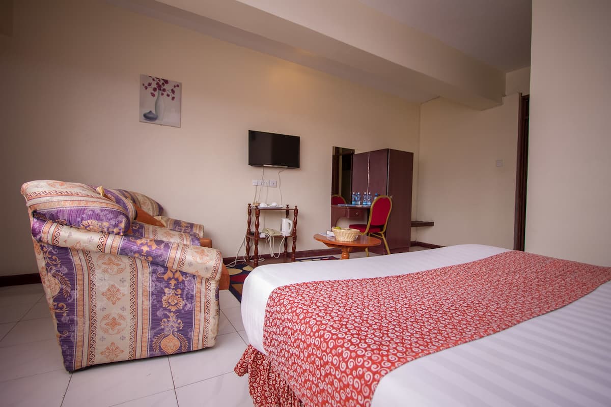 Une chambre d’hôtel comprenant un lit, un canapé, une télévision, une armoire et une petite table avec une chaise.