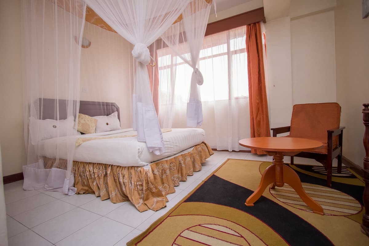 Une chambre à coucher avec un lit, une chaise et une fenêtre avec des rideaux.