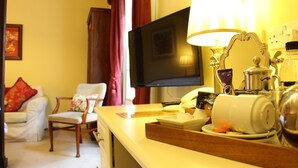A hotel room with a flat-screen TV, a bedside table with a lamp, a chair, and a sofa. - Moortown Lodge 1760 (Ringwood)