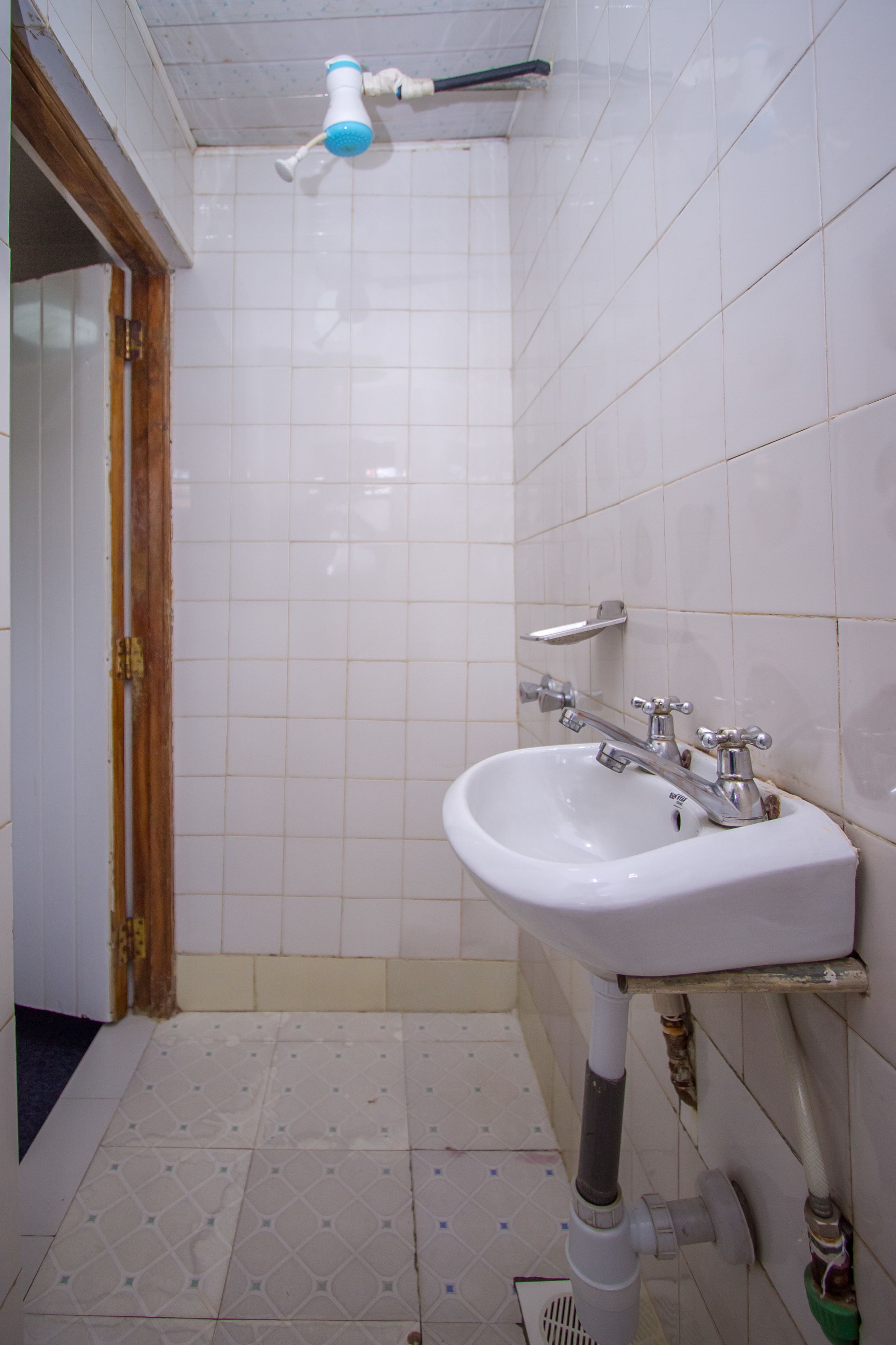Un baño con lavamanos blanco, un espejo y un cabezal de ducha.