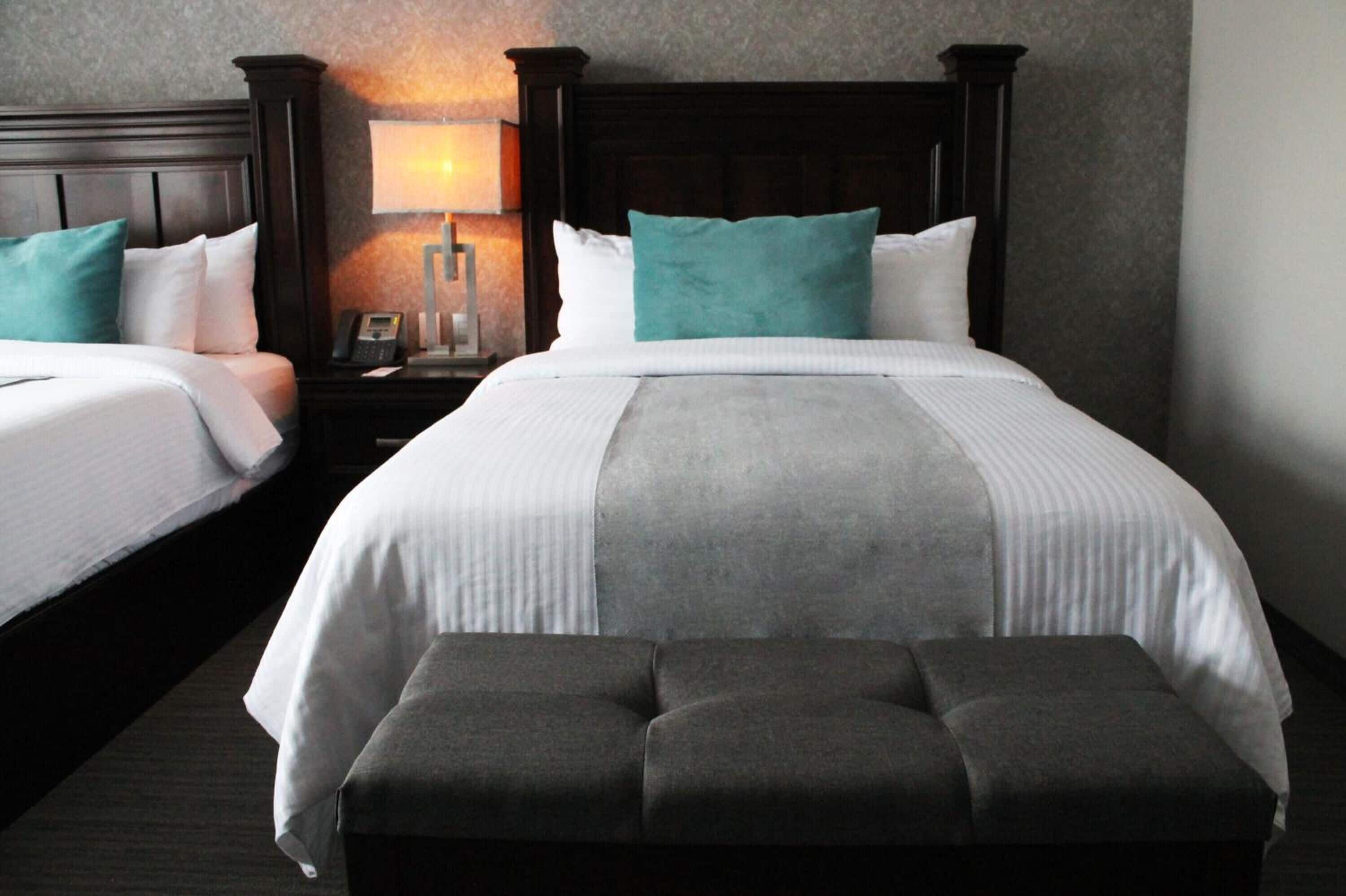 Une chambre d’hôtel avec deux lits, une table de chevet avec une lampe et un banc.
