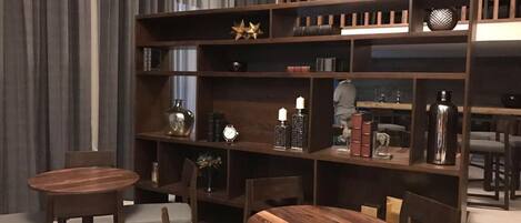 Una biblioteca moderna con estanterías de madera, dos mesas redondas y asientos cómodos.
