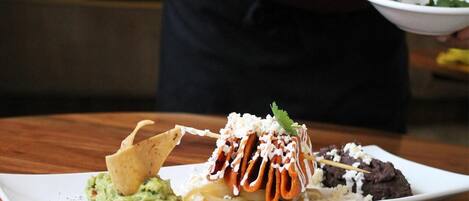 Um prato de nachos com diversos acompanhamentos e guacamole.