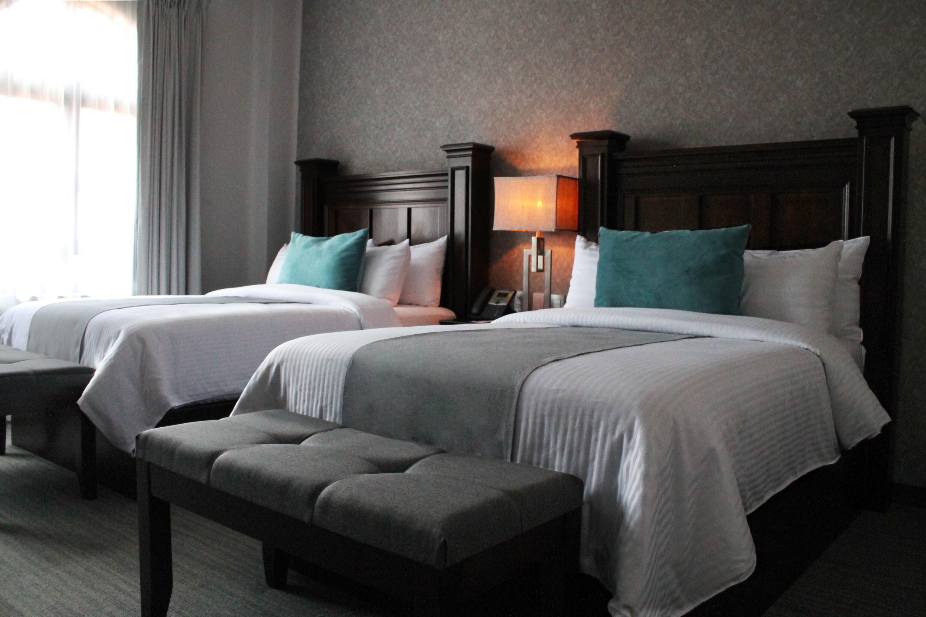 Una habitación de hotel con dos camas, un banco y una lámpara.