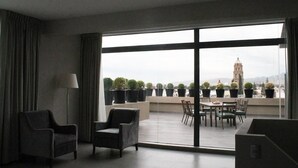 A modern hotel room with a large balcony, a dining area, and a view of a cityscape including a tower. - Gran Hotel Concordia San Luis Potosí (San Luis Potosi)