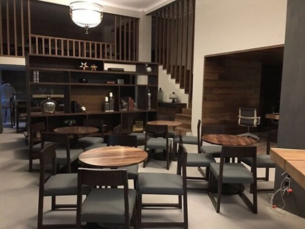 A modern interior with round tables and chairs, wooden shelves, and a staircase. - Gran Hotel Concordia San Luis Potosí (San Luis Potosi)