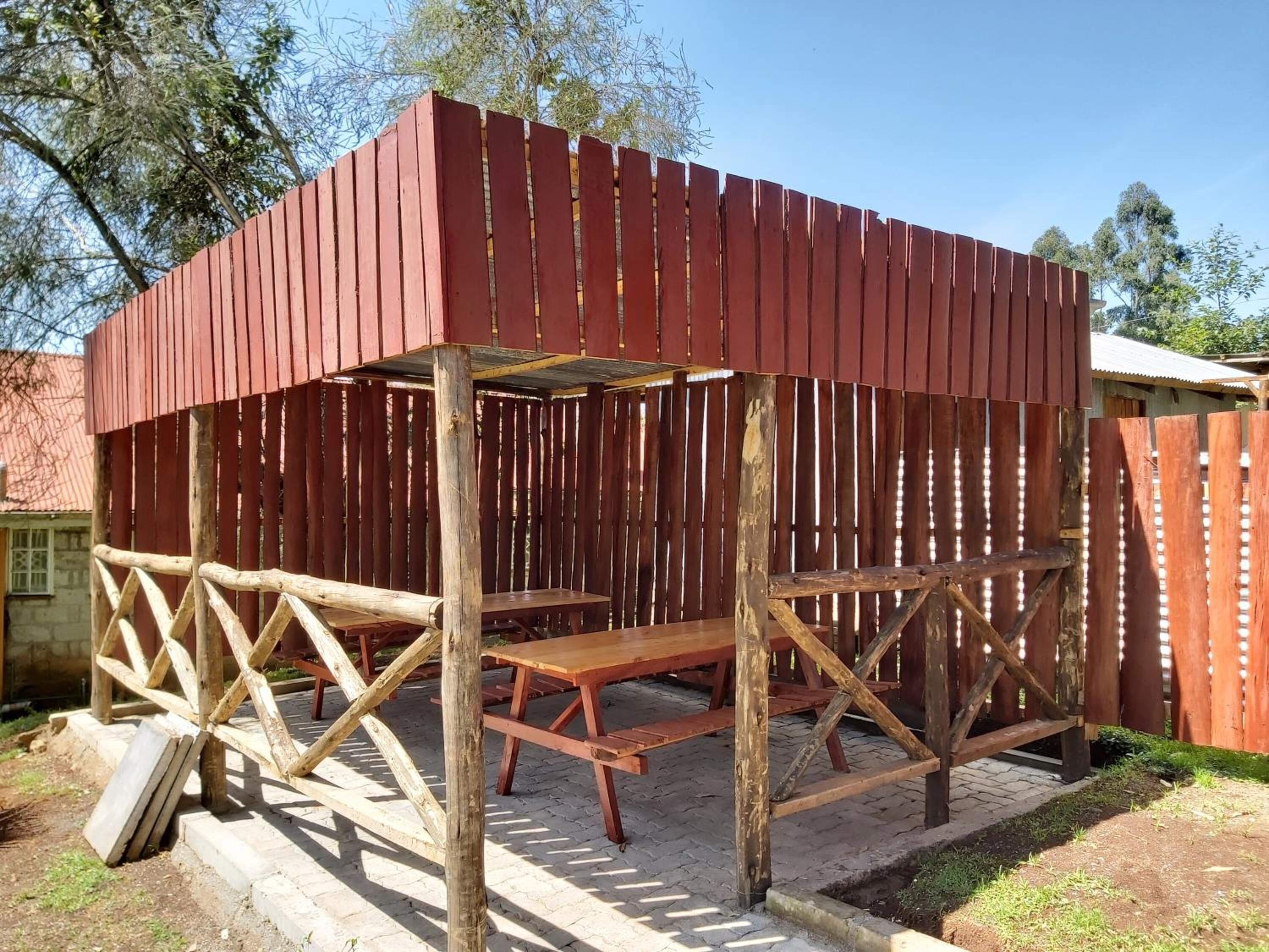 A wooden structure with a bench and a table, surrounded by a fence.