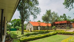 A building with a red roof, surrounded by well-maintained gardens and trees. - Sahara Gardens Kericho (Kericho)
