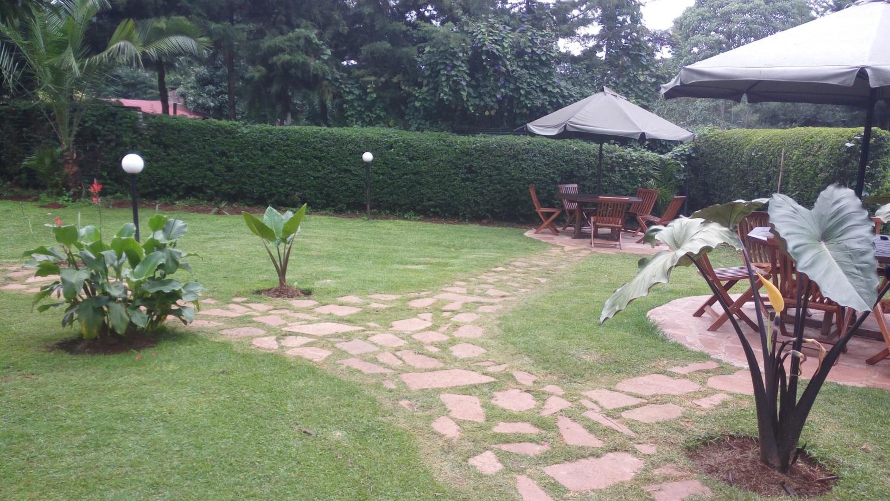 Ein Garten mit einem Kiesweg, Gartenmöbeln und einer Hecke.