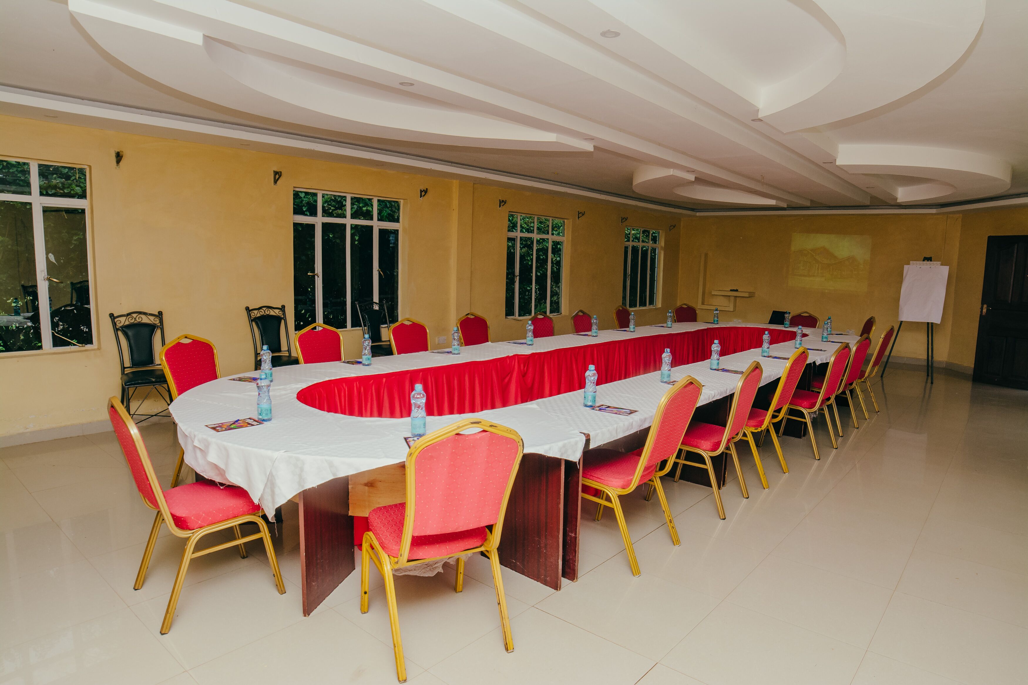 A conference room with a long table, red chairs, and water bottles.