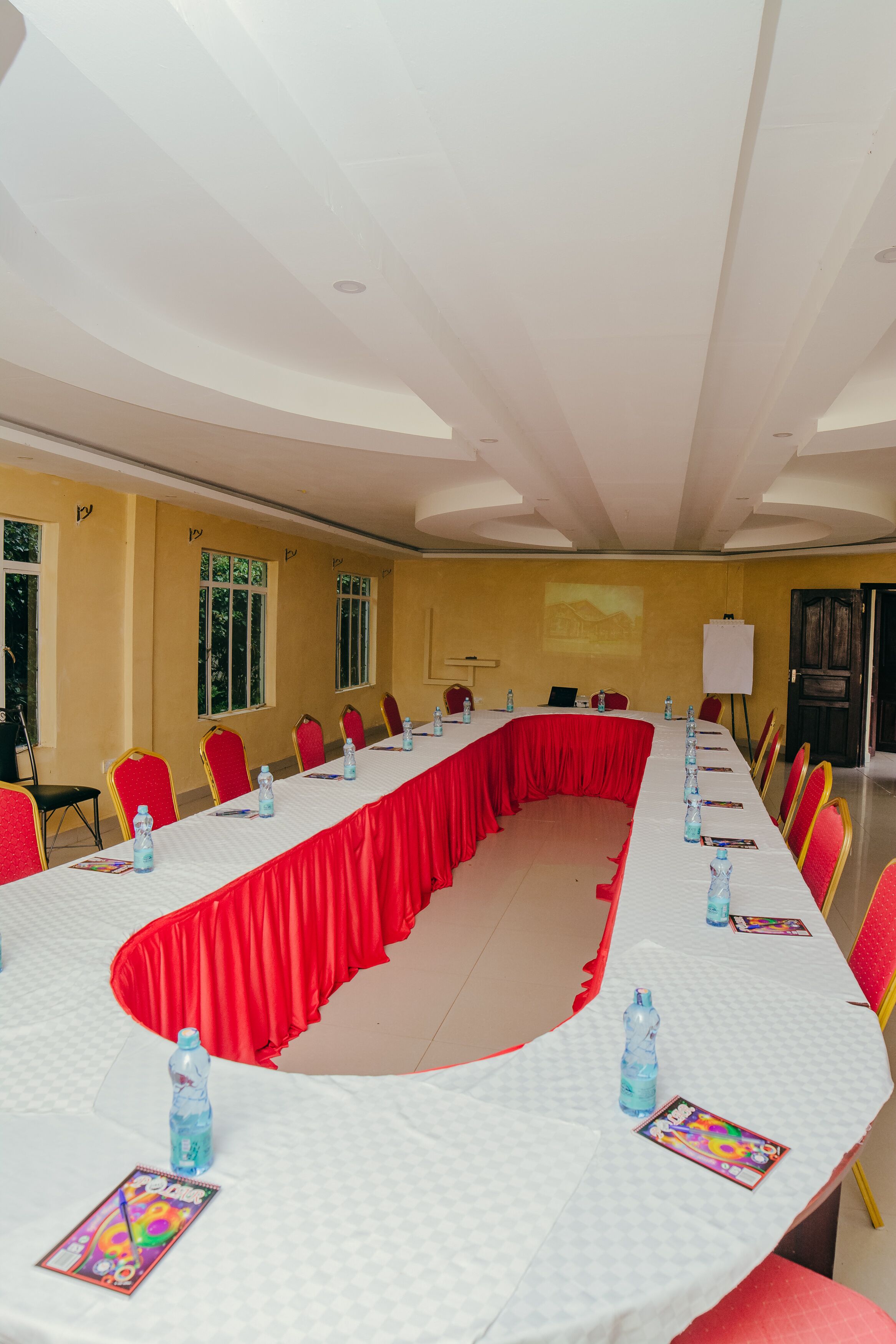 A conference room with a long table, red chairs, and water bottles.