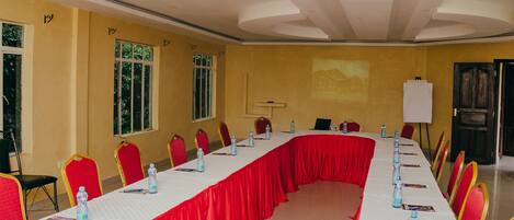 A conference room with a long table, red chairs, and water bottles.