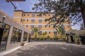 A multi-story building with large windows and a courtyard with potted plants. - Emboita Hotel (Nakuru)