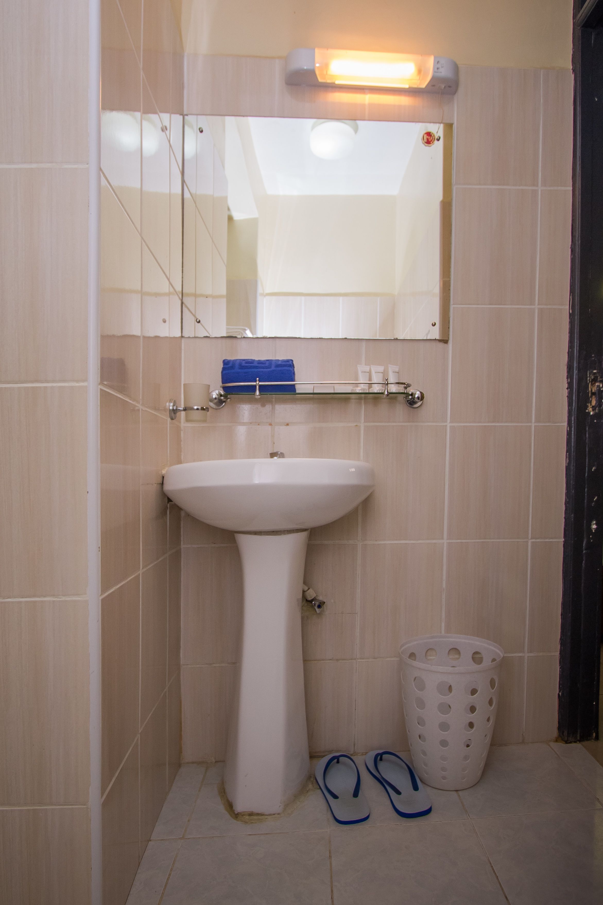 A bathroom with a white sink, a mirror, and a laundry basket.
