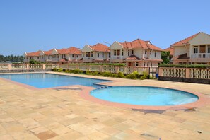 A resort with multiple swimming pools and a row of villas with red-tiled roofs.