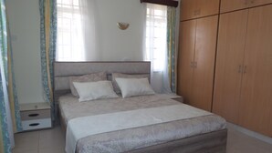 A bedroom with a bed, a wardrobe, and curtains. - Azanza Mtwapa Holiday Home (Mtwapa)
