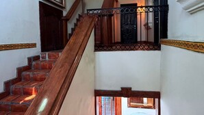 Una escalera con barandilla de madera, ventilador de techo y puerta con reja negra.